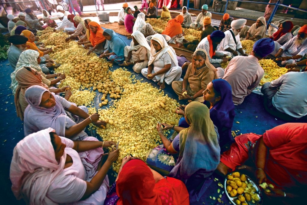 Volunteers peeling potatoes together in Langar