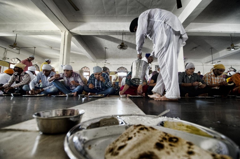 Volunteers serving food in long rows of diners