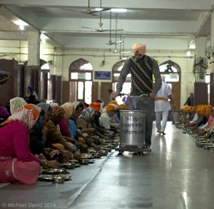 Diners sitting on the floor receiving water and food